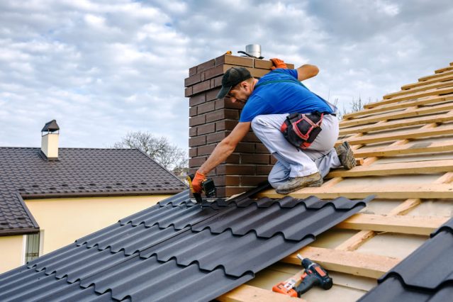 Roofer With Electric Screwdriver Covers Repairs The Roof — URB’n Roofing In Gumdale, QLD